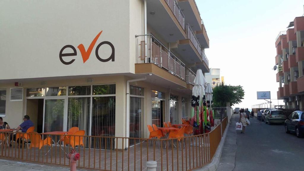 - un bâtiment avec des tables et des chaises orange à l'extérieur dans l'établissement Hotel Eva, à Ravda