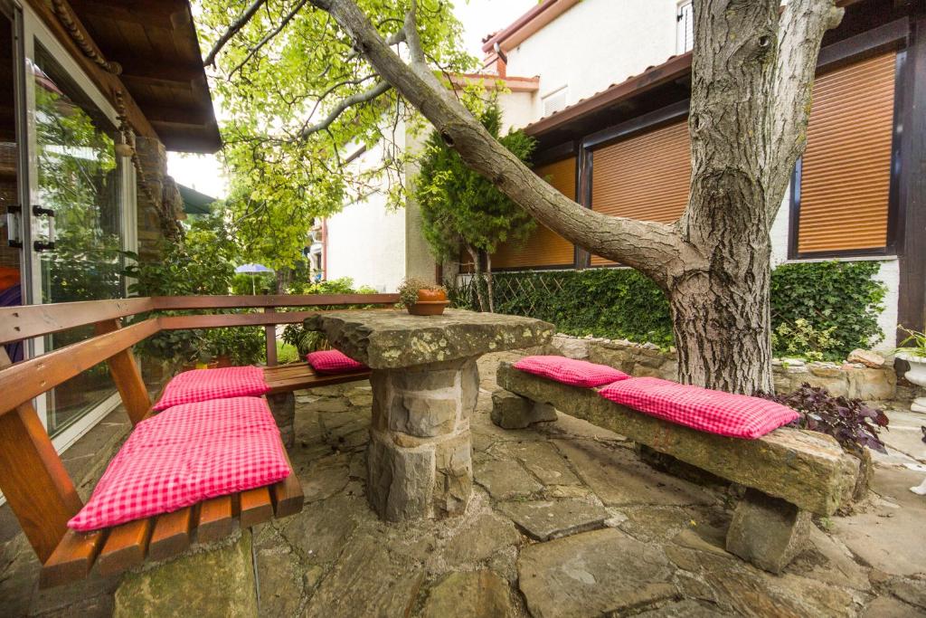 two benches with red cushions sitting next to a tree at Apartments Baredi in Izola