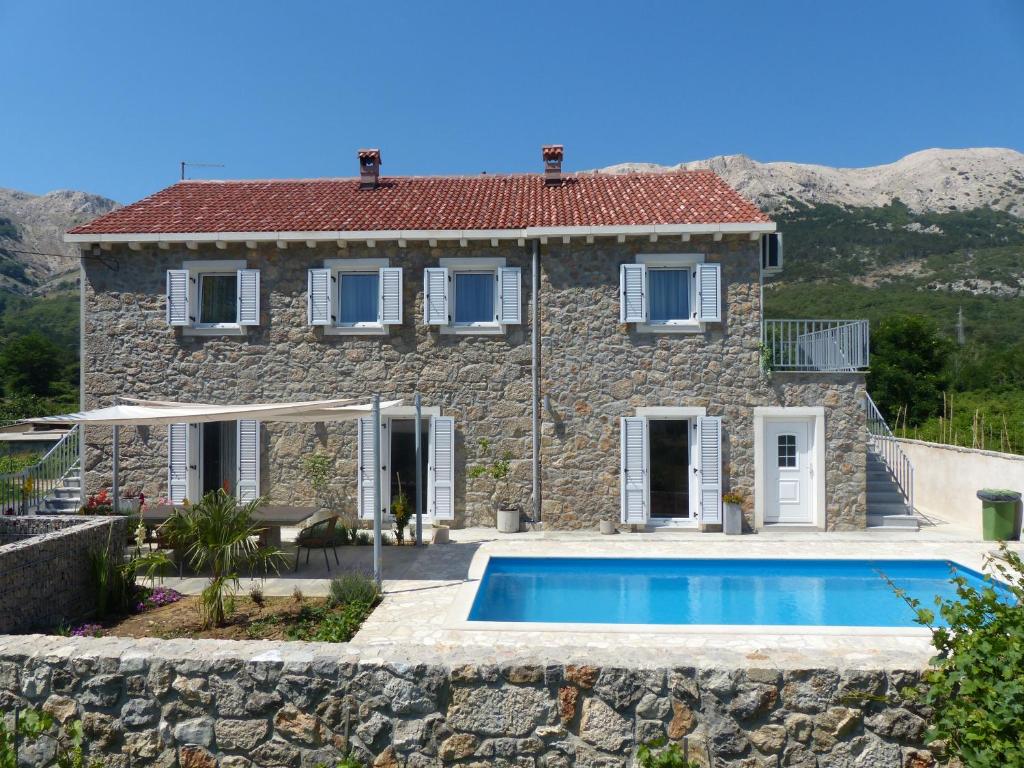 Draga Bašćanska的住宿－Villa Manuela，一座石头房子,前面设有一个游泳池