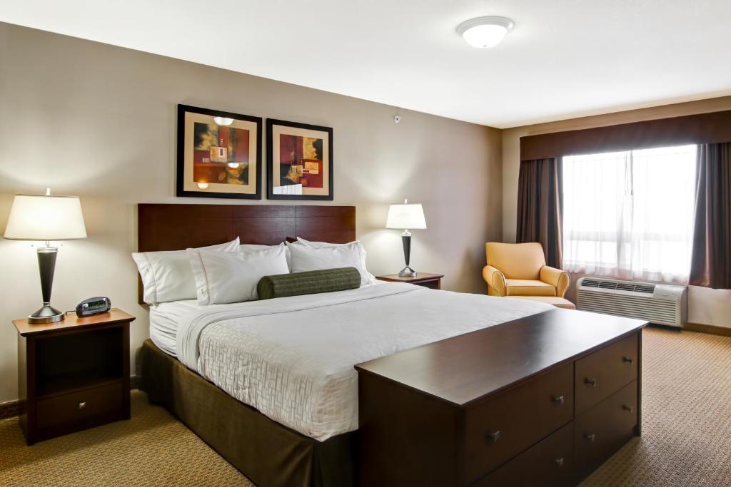 um quarto de hotel com uma cama grande e uma cadeira em Canalta Oyen em Oyen