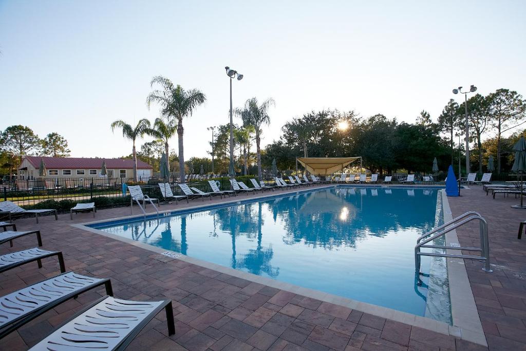 a large swimming pool with lounge chairs and palm trees at Orlando RV Resort in Orlando
