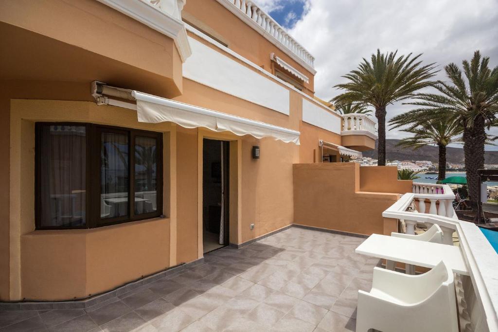 a building with a patio with a pool and palm trees at TRG Studio in Arona