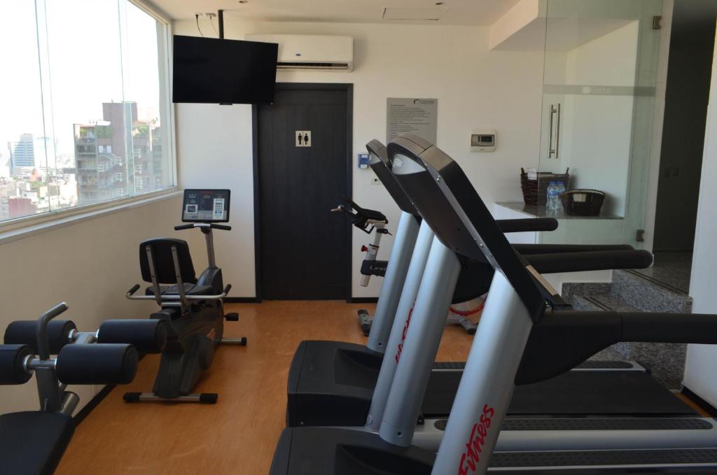 A small cardio room with treadmills, a bike, and a city-facing window.