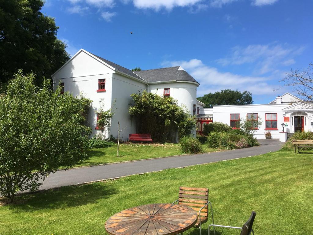 une maison blanche avec un parasol dans l'herbe dans l'établissement The Burren Hostel - Sleepzone, à Lisdoonvarna