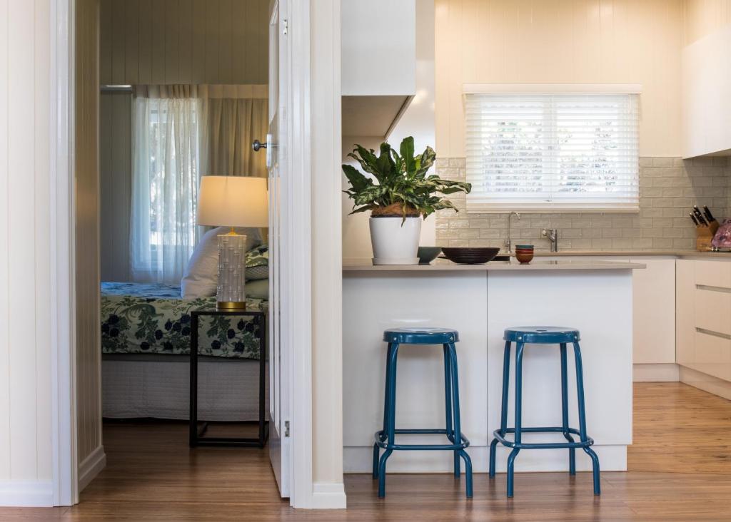 a kitchen with two blue stools in front of a counter at Keeler Cottage in Toowoomba