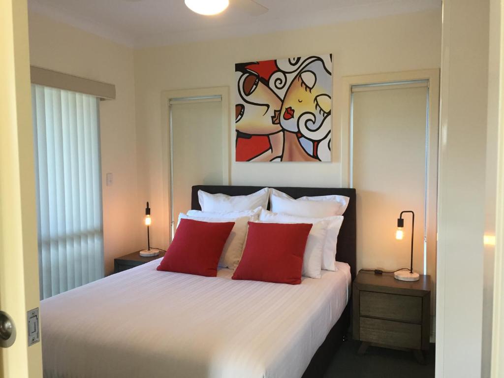 1 dormitorio con 1 cama blanca grande con almohadas rojas en Lyreen's Apartment, en Auburn