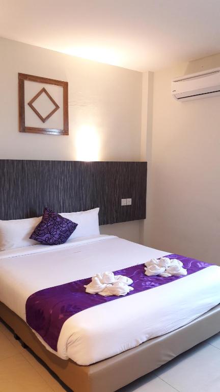 a hotel room with a large bed with purple sheets at Salsa Resort Langkawi By Casa Loma in Pantai Cenang