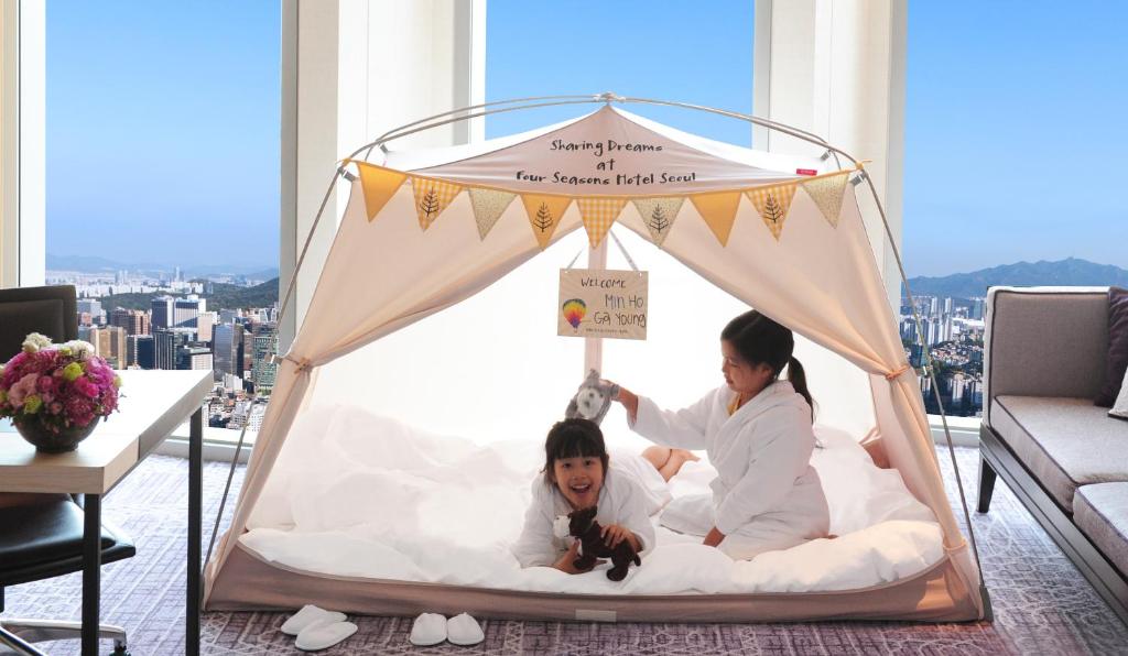 a woman and a child in a canopy bed at Four Seasons Hotel Seoul in Seoul