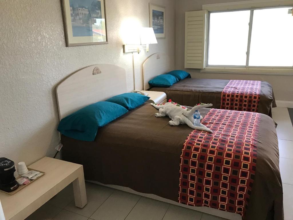 duas camas num quarto de hotel com um bicho de peluche na cama em Apollo Inn - Cocoa em Cocoa