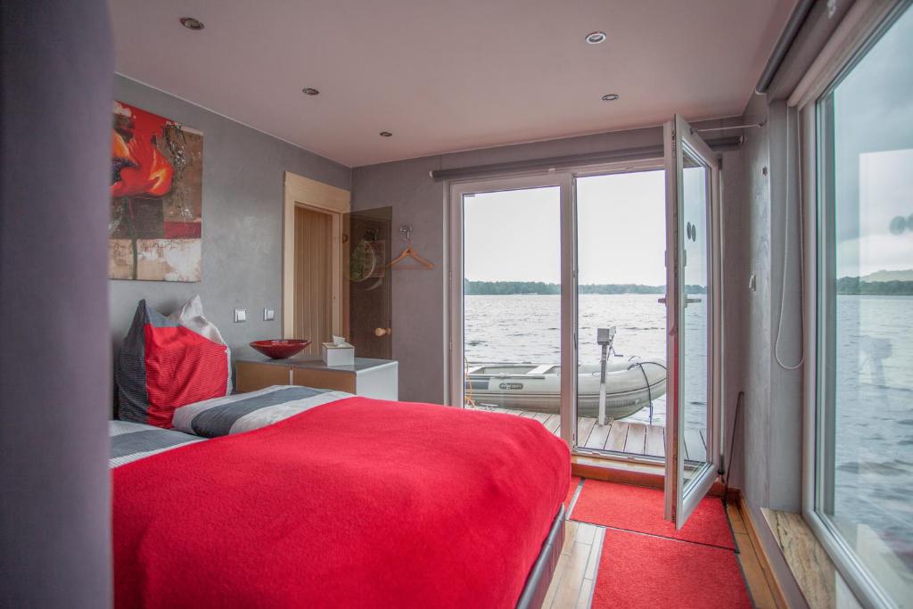 ein Schlafzimmer mit einem großen roten Bett und einem Boot im Wasser in der Unterkunft Hausboot DeLuxe in Berlin