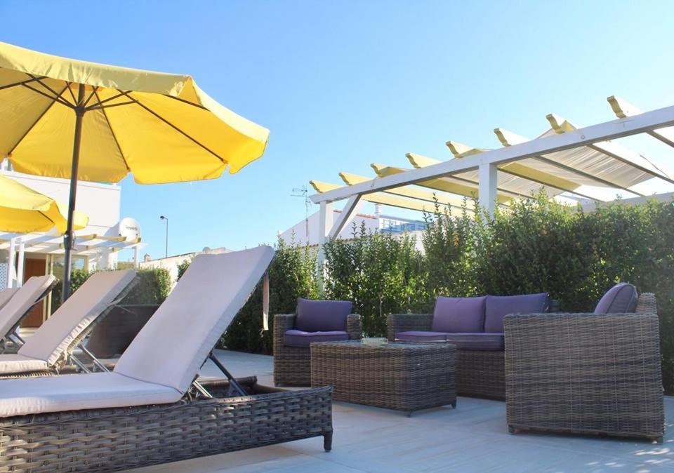 eine Terrasse mit Liegestühlen und einem Sonnenschirm in der Unterkunft Quinta Da Rosa Linda in Monte Gordo