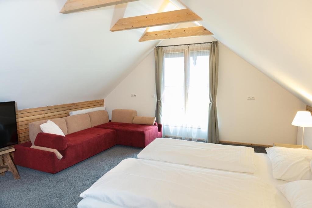 1 dormitorio con 2 camas y sofá rojo en Weinberg Lodge - Presshaus, en Klöchberg