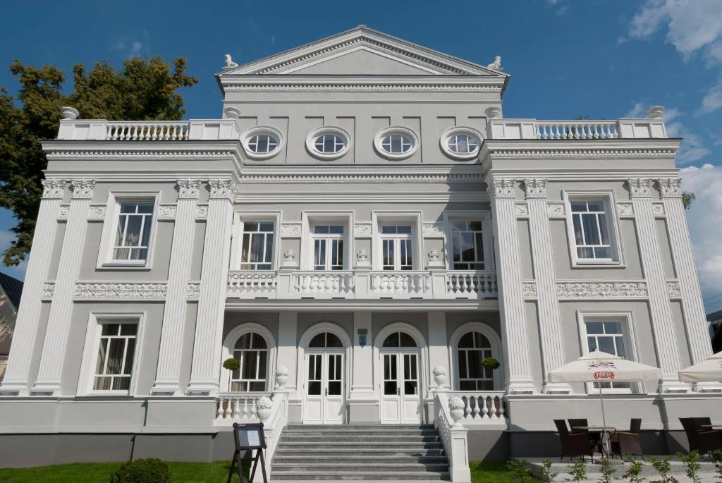 a large white building with stairs in front of it at Hotel Willa Hueta in Kielce