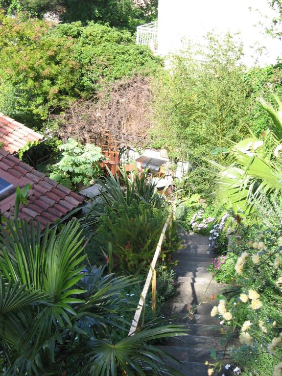 un jardin avec des plantes et des arbres et une passerelle dans l'établissement Studio Grotte des fées, à Hyères