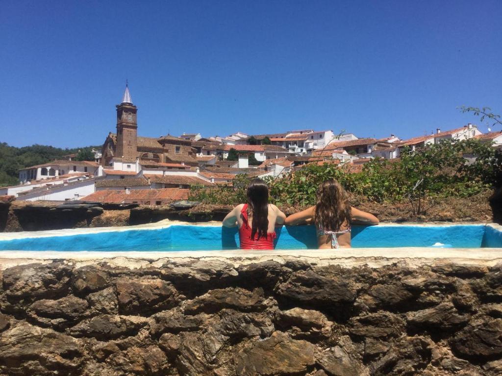 Dos chicas están sentadas en una piscina en El Zarzo de Nemesio, patio barbacoa 2 Hab 4 Pers mas 2 Max, en Valdelarco