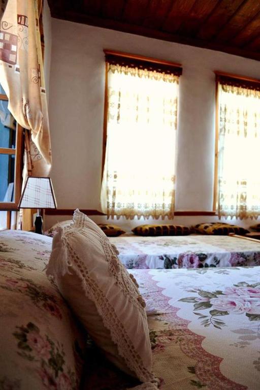 a bedroom with two beds and two windows at Guest House Vasili in Berat