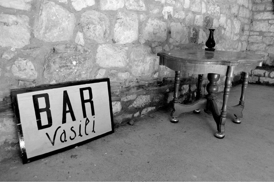 a table with a sign on it next to a wall at Guest House Vasili in Berat