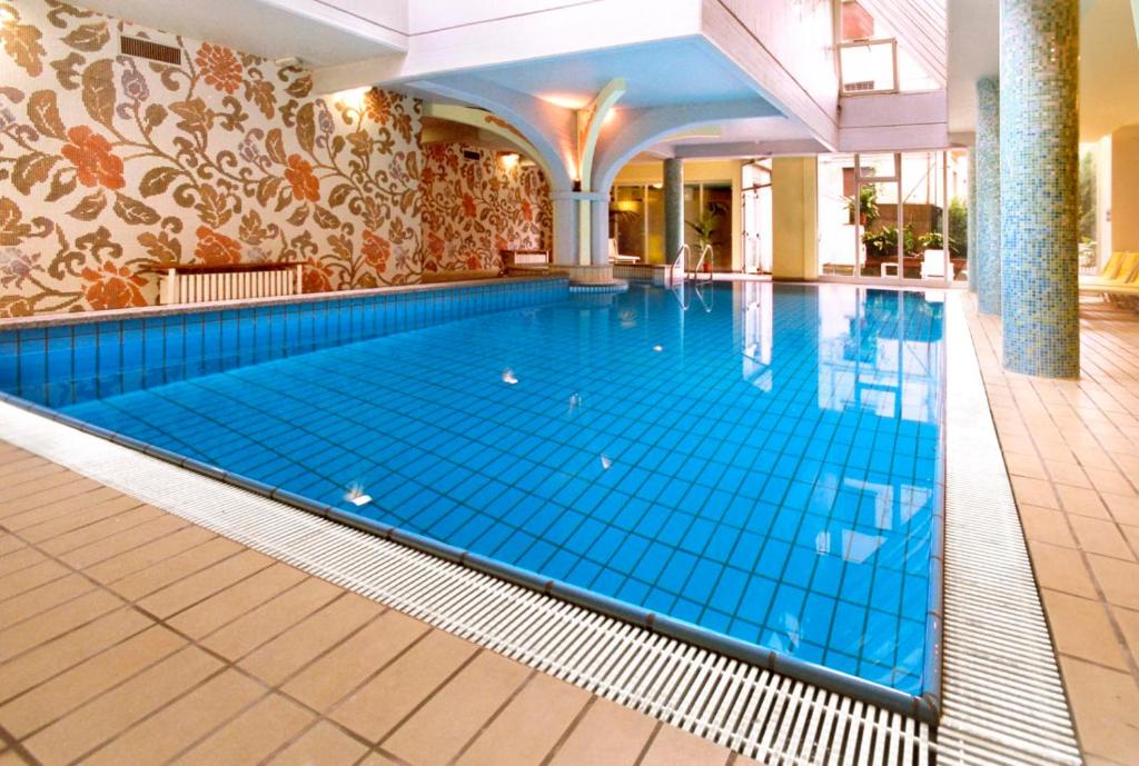 a large swimming pool in a hotel with a blue floor at Hotel Ferrari in Salsomaggiore Terme