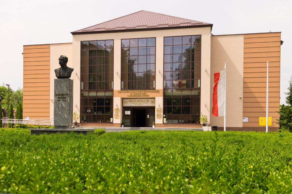 un edificio con una estatua delante de él en Pokoje Gościnne w Centrum Kultury Wsi Polskiej, en Wierzchoslawice