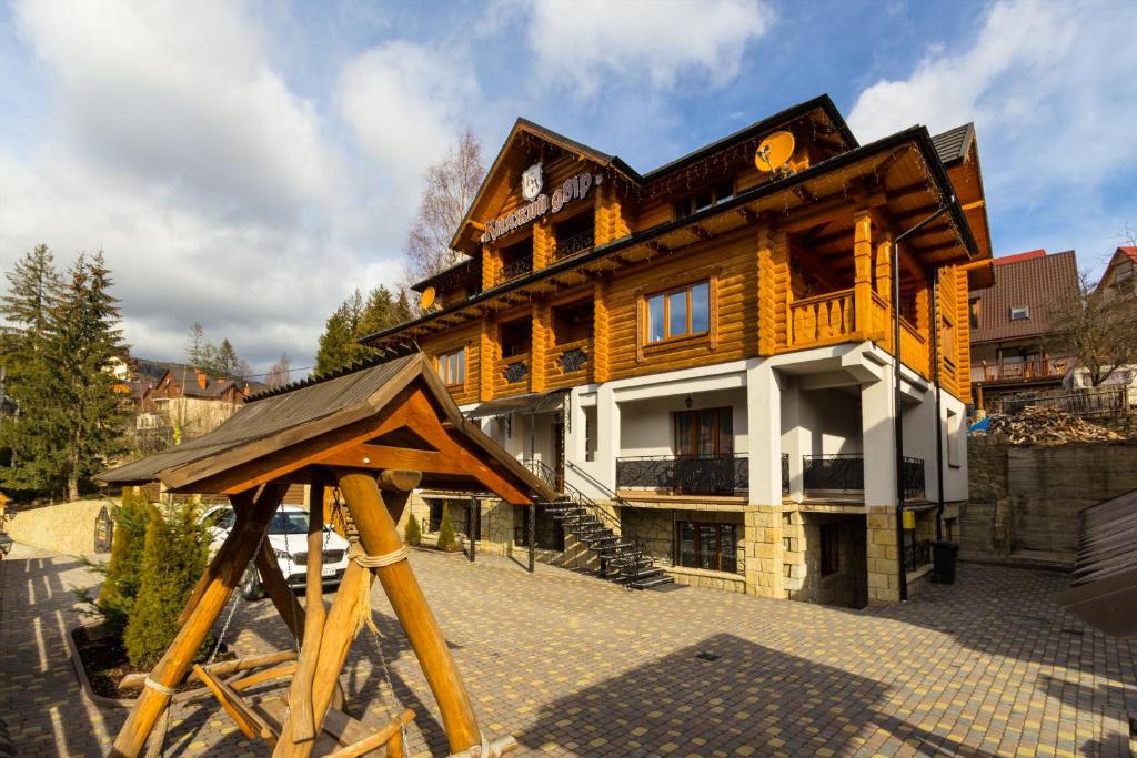 un grand bâtiment en bois avec un toit en bois dans l'établissement Knyazhyj Dvir, à Yaremtche