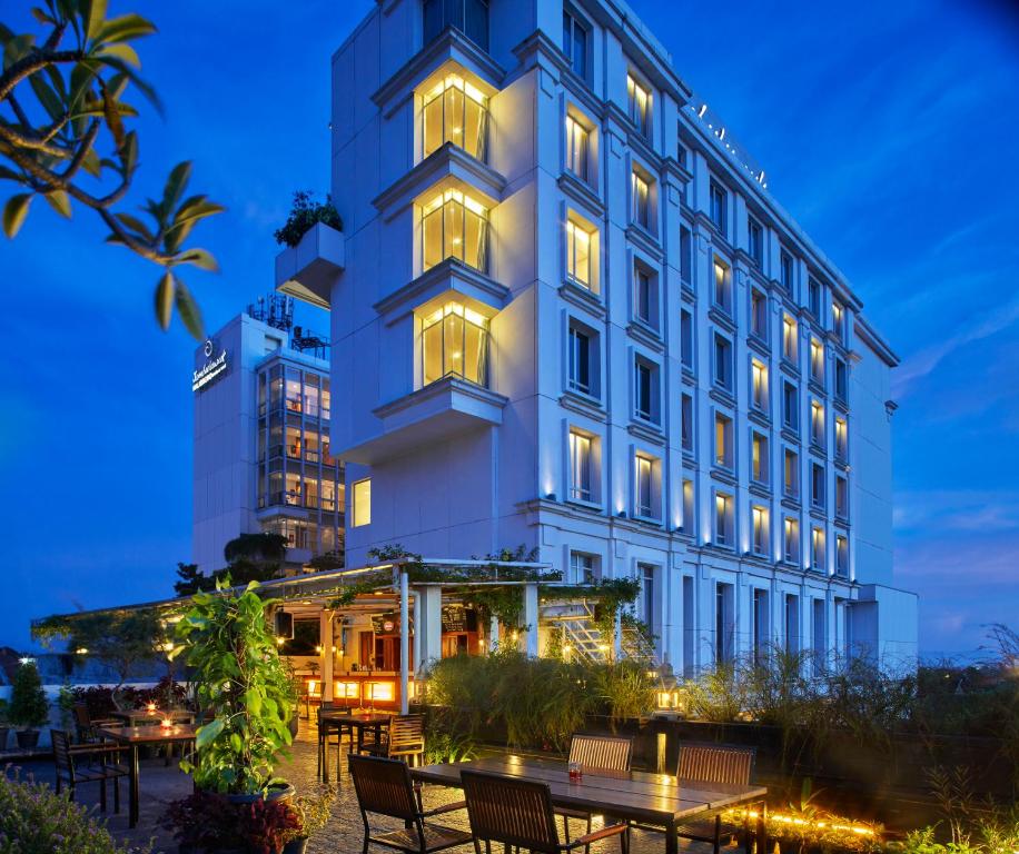 a hotel with tables and chairs in front of a building at Jambuluwuk Malioboro Hotel Yogyakarta in Yogyakarta