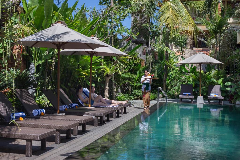 a woman standing next to a swimming pool in a resort at Grand Sehati & Spa, Ubud in Ubud