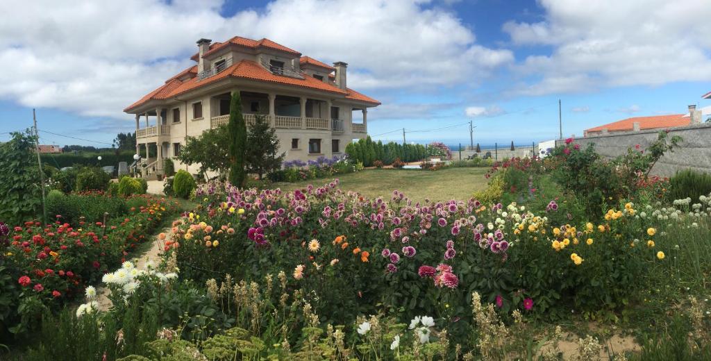 una casa con un jardín de flores delante de ella en Pensión Residencia A Cruzán, en Noalla