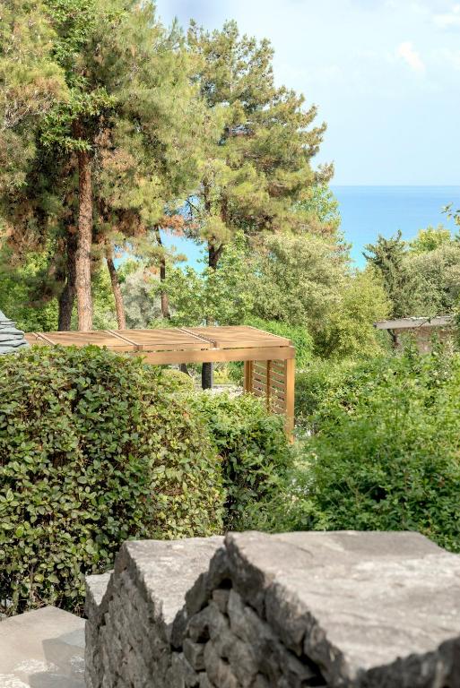 a wooden bench in front of a bush with a tree at Makryammos in Limenas