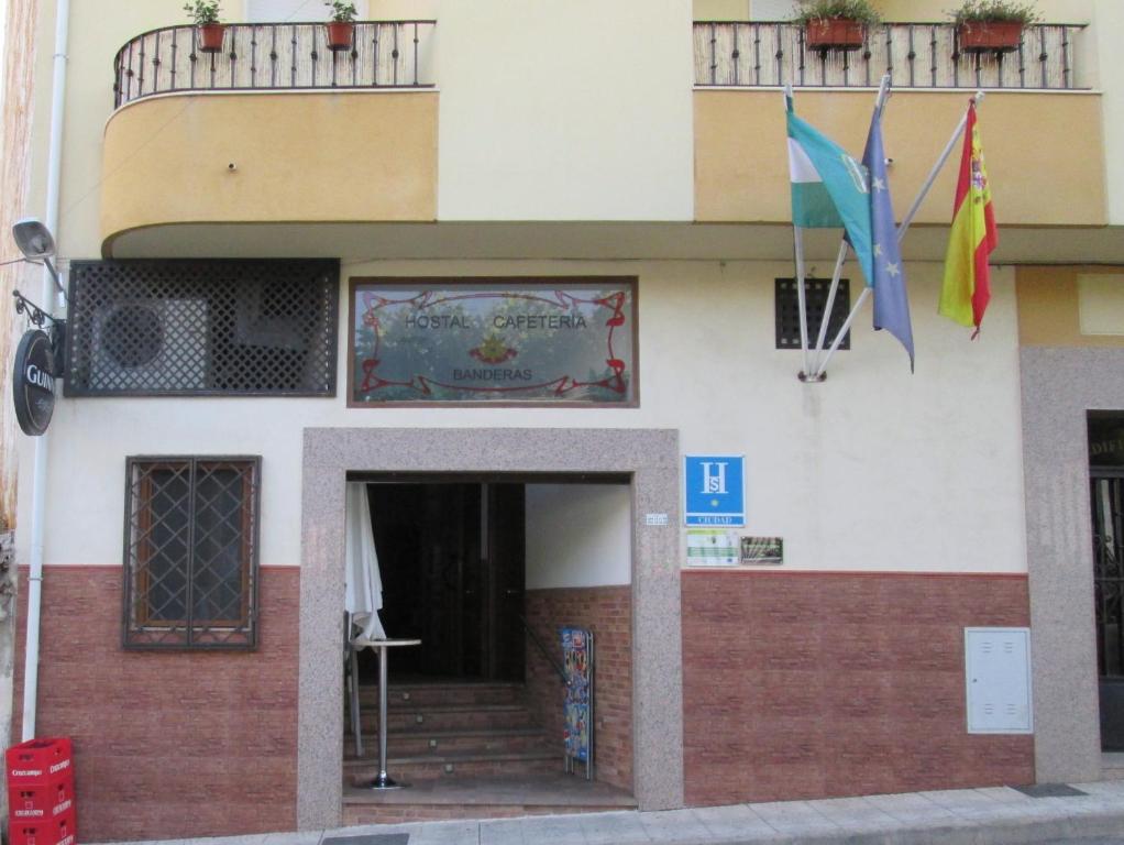 un bâtiment avec drapeaux devant lui dans l'établissement Hostal Banderas, à Fuensanta de Martos