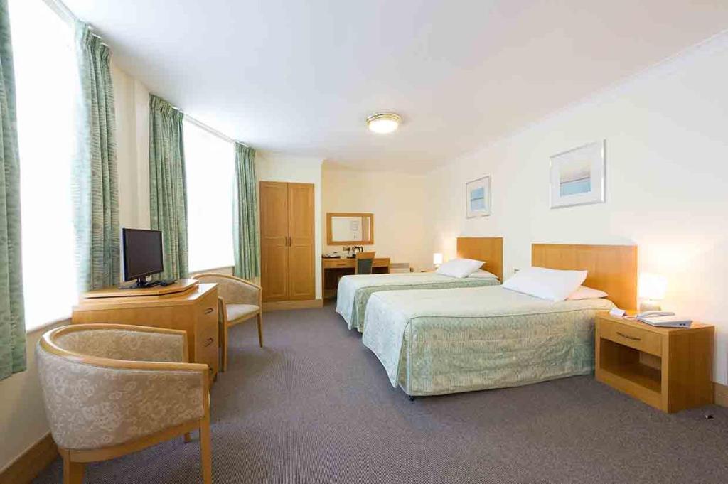 una camera d'albergo con due letti e una televisione di The Rutland Hotel a Douglas