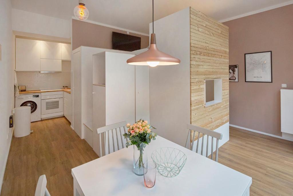 eine Küche und ein Esszimmer mit einem Tisch mit Blumen darauf in der Unterkunft Modern Design Apartment in Berlin