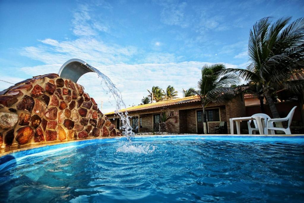 a swimming pool with a water fountain in front of a house at Mar à vista in Canoa Quebrada