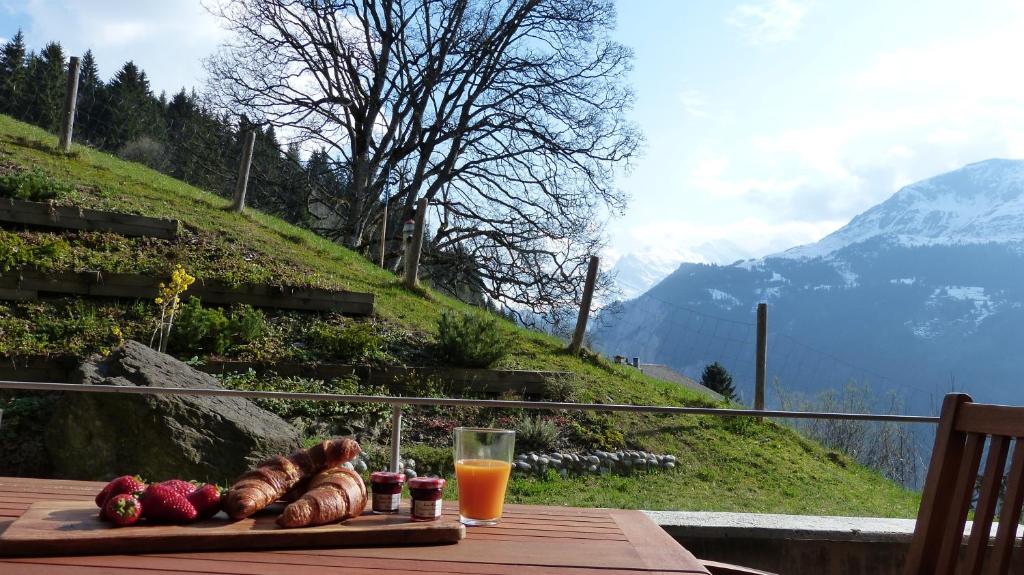 a table with a plate of food and a glass of orange juice at Roossi-Huus 2 in Wengen