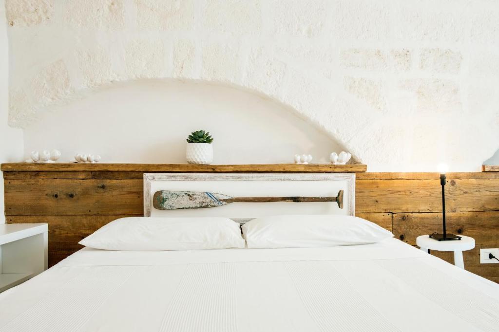sypialnia z białym łóżkiem z drewnianym zagłówkiem w obiekcie Borgo Albergo Capozzi 37 w mieście Monopoli