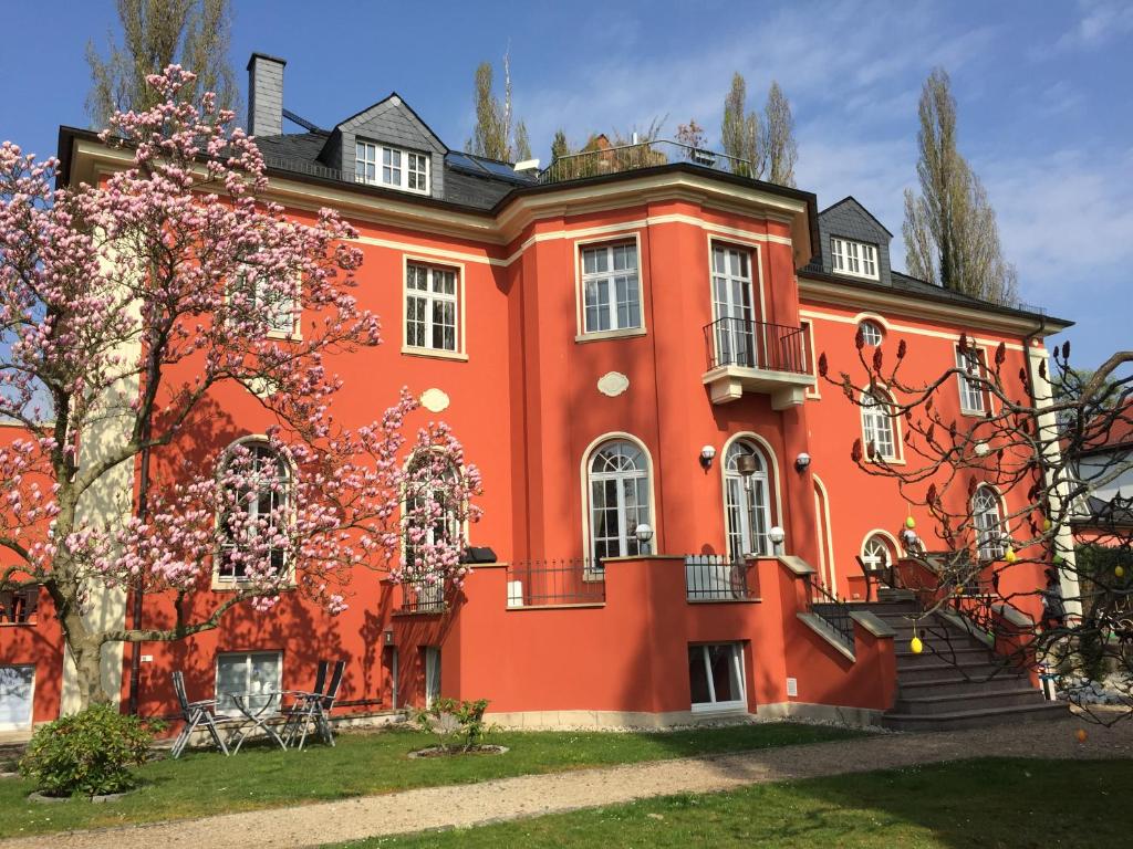 un grand bâtiment orange avec un arbre dans l'établissement Villa am Park Apartment, à Dresde