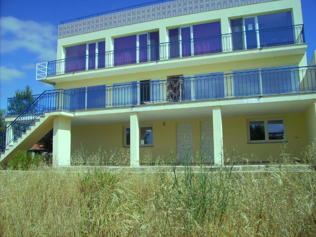 Villa Ortiga في ماساو: منزل أصفر مع شرفات زرقاء في الأعلى