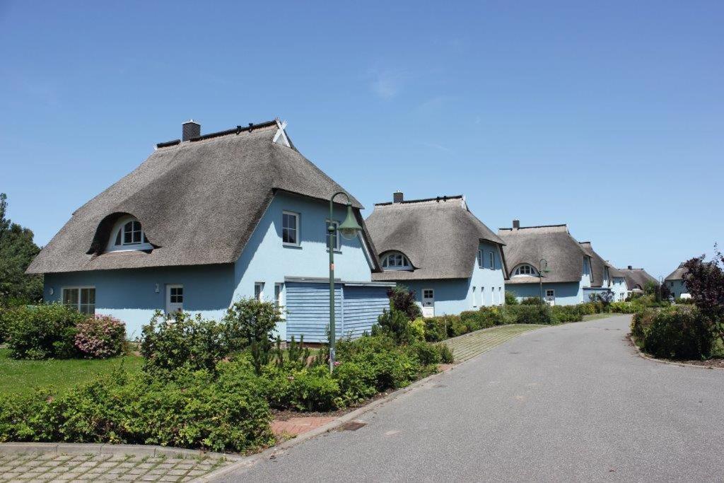 una fila de casas con techos de paja en una calle en Ferienpark Arielle, en Börgerende-Rethwisch