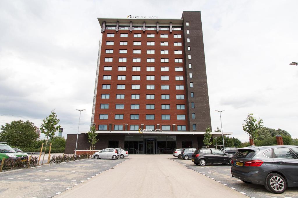 a large building with cars parked in a parking lot at Bastion Hotel Eindhoven Waalre in Eindhoven