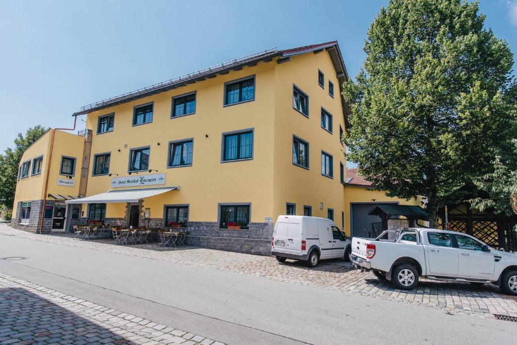 un edificio amarillo con dos coches estacionados frente a él en Gasthof Metzgerei Linsmeier, en Iggensbach