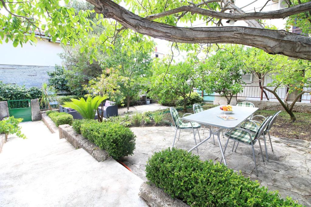 un patio con mesa y sillas bajo un árbol en Apartments Lavanda, en Primošten