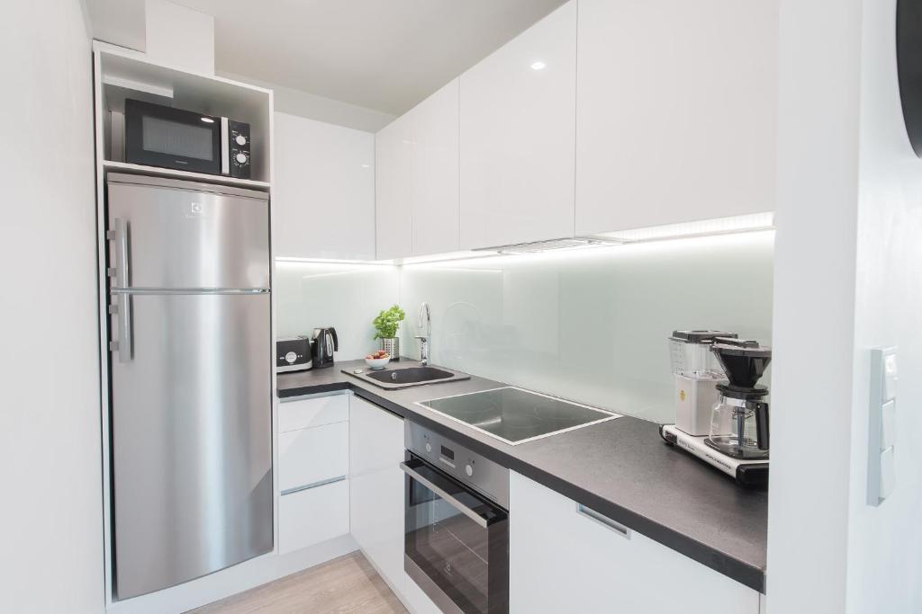 a kitchen with white cabinets and a stainless steel refrigerator at Forenom Serviced Apartments Helsinki Lauttasaari in Helsinki