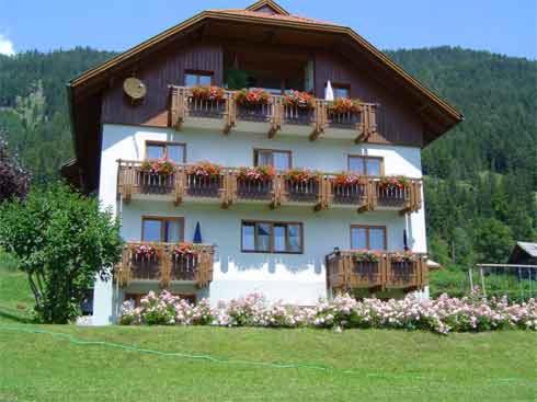 ein Haus mit Balkonen und Blumen davor in der Unterkunft Haus Rohr in Weissensee