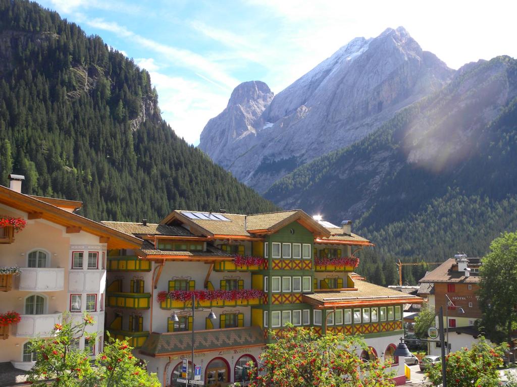 a building with a mountain in the background at Hotel Alpino Al Cavalletto in Canazei