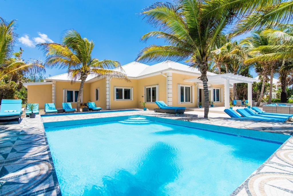 una piscina frente a una casa con palmeras en Sprat Bay Luxury Villa, en Half Way Pond