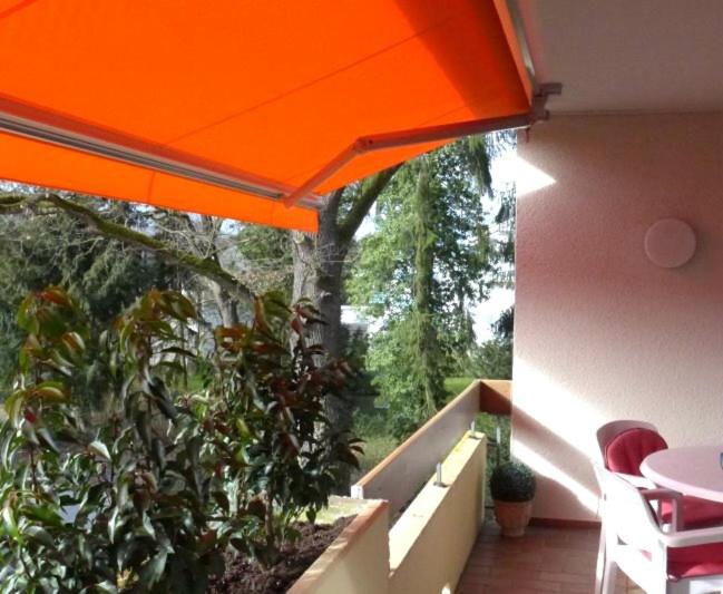 an orange umbrella over a balcony with plants at Appartementhaus im Grün in Bad Bellingen