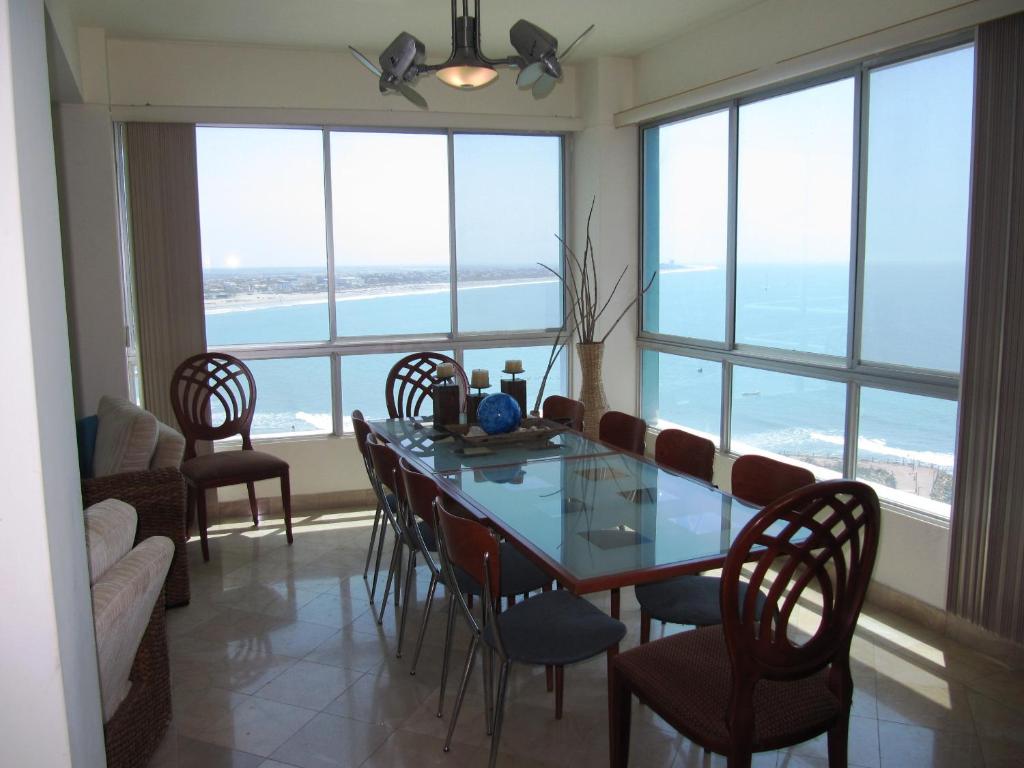 una sala da pranzo con tavolo, sedie e finestre di Penthouse de lujo. Carabelas de Colón a Playas