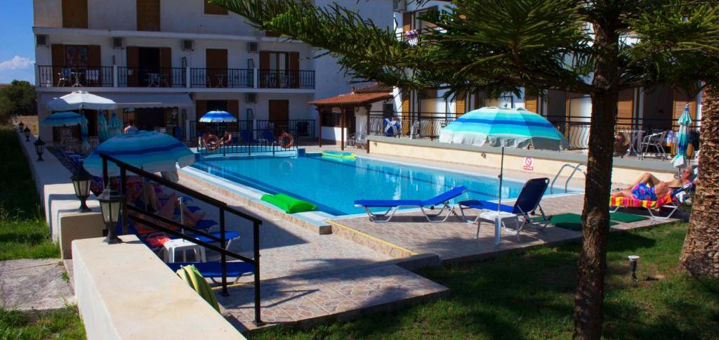 - une piscine avec des chaises et des parasols à côté d'un bâtiment dans l'établissement Litsa Studios, à Alikanas