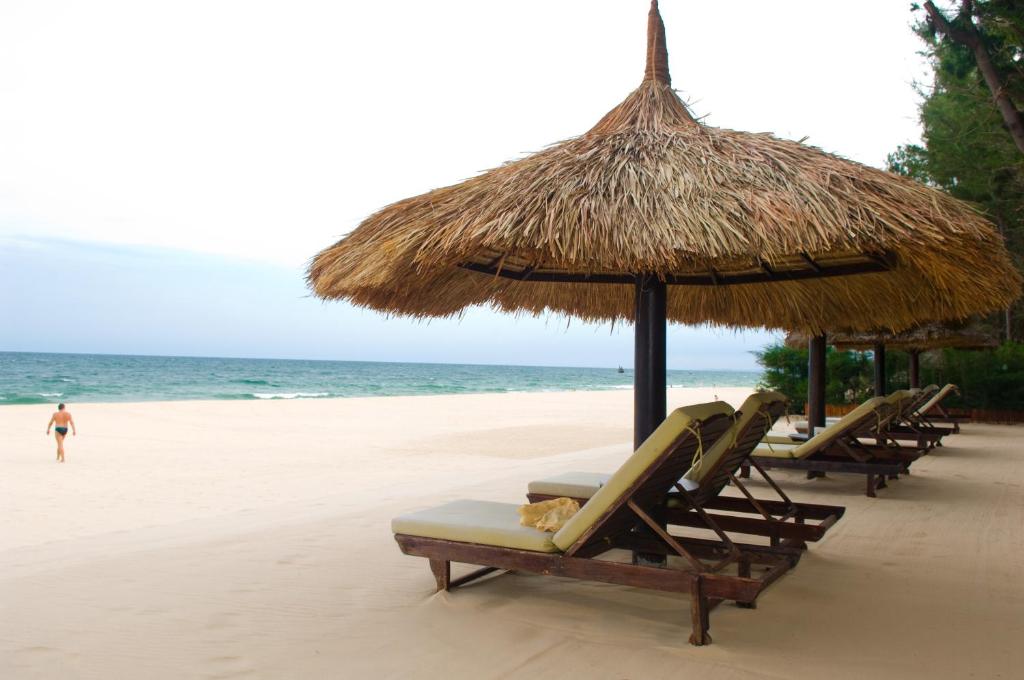 - un groupe de chaises longues et de parasols sur une plage dans l'établissement Cham Villas Resort, à Mui Ne