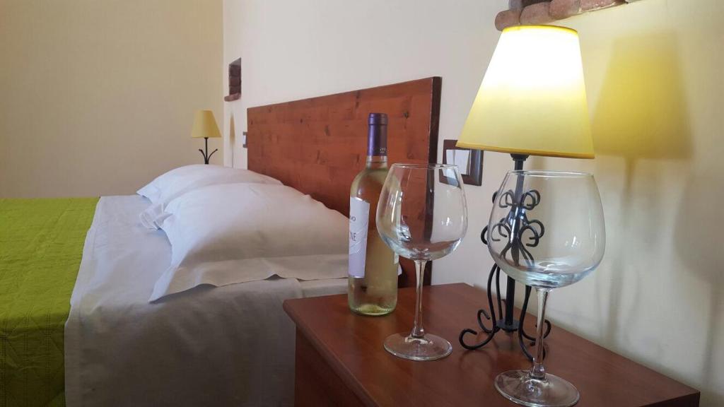 una camera da letto con un letto con una lampada e due bicchieri da vino di Camere Con Terrazzino a Valderice