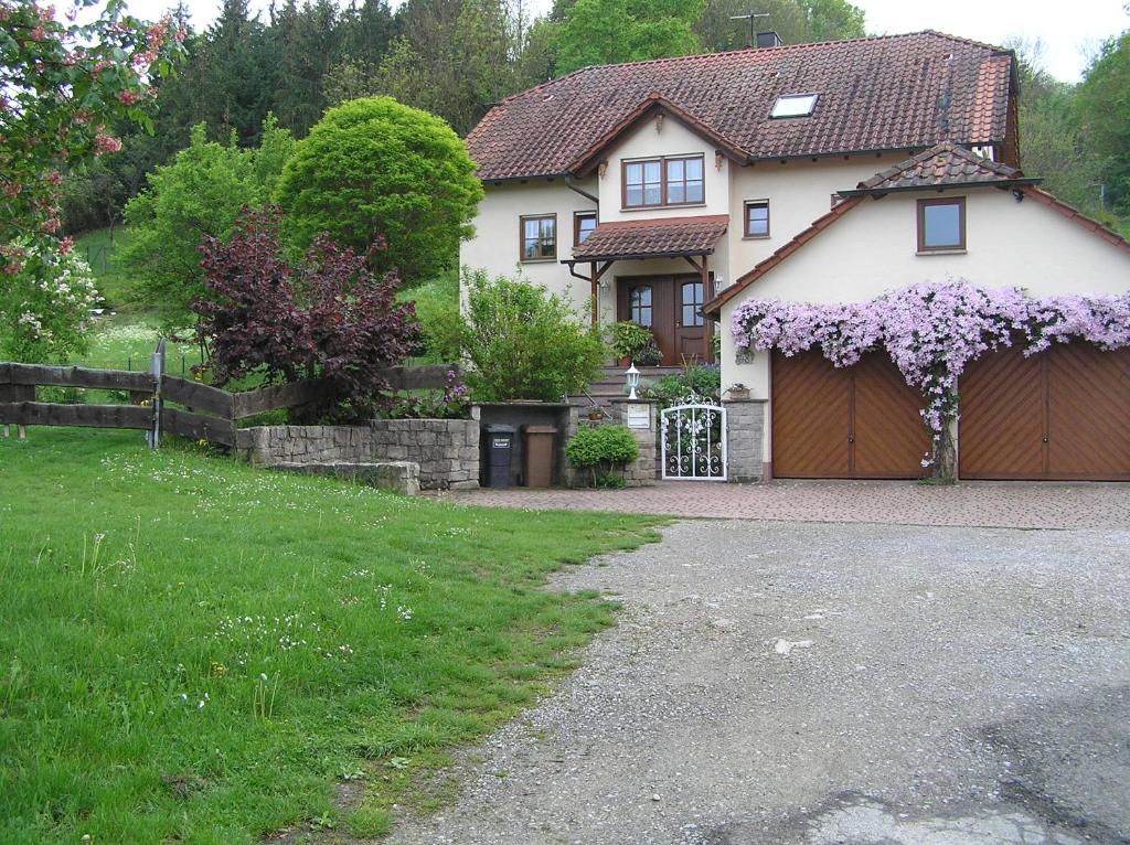 Una casa con un garaje con flores púrpuras. en Ferienwohnung Am Alten Berg, en Ochsenfurt
